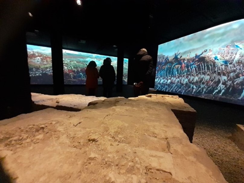 Bezoekers bekijken historische tentoonstelling in donker museum.