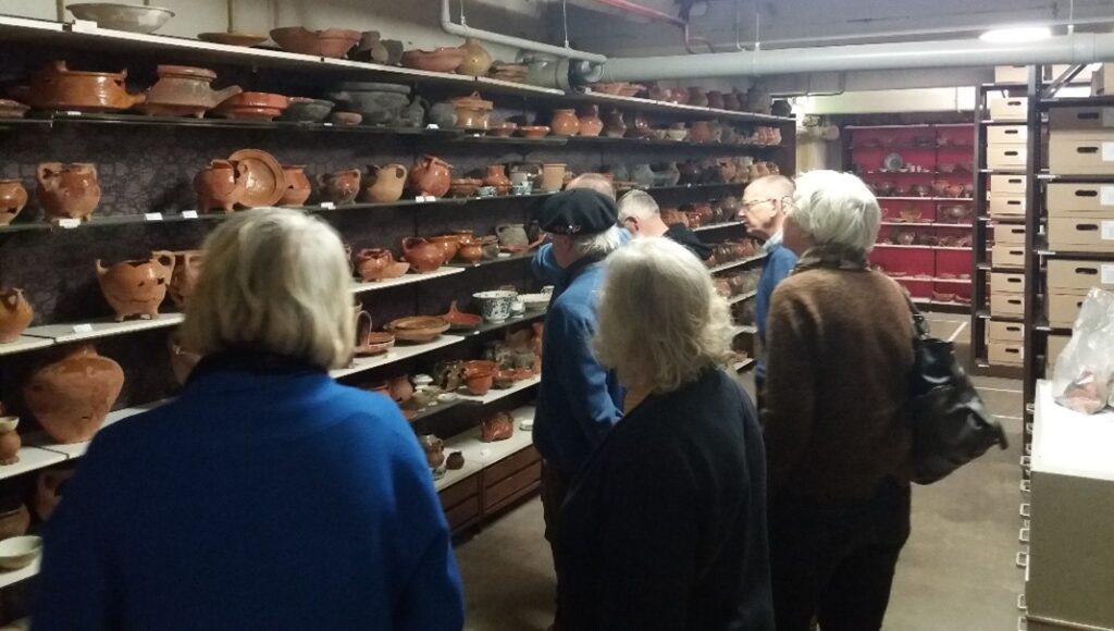 Mensen bekijken antieke aardewerkcollectie in museumkelder