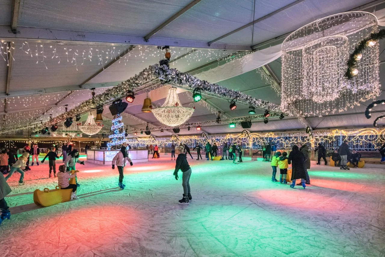 Mensen schaatsen op kleurrijke overdekte schaatsbaan