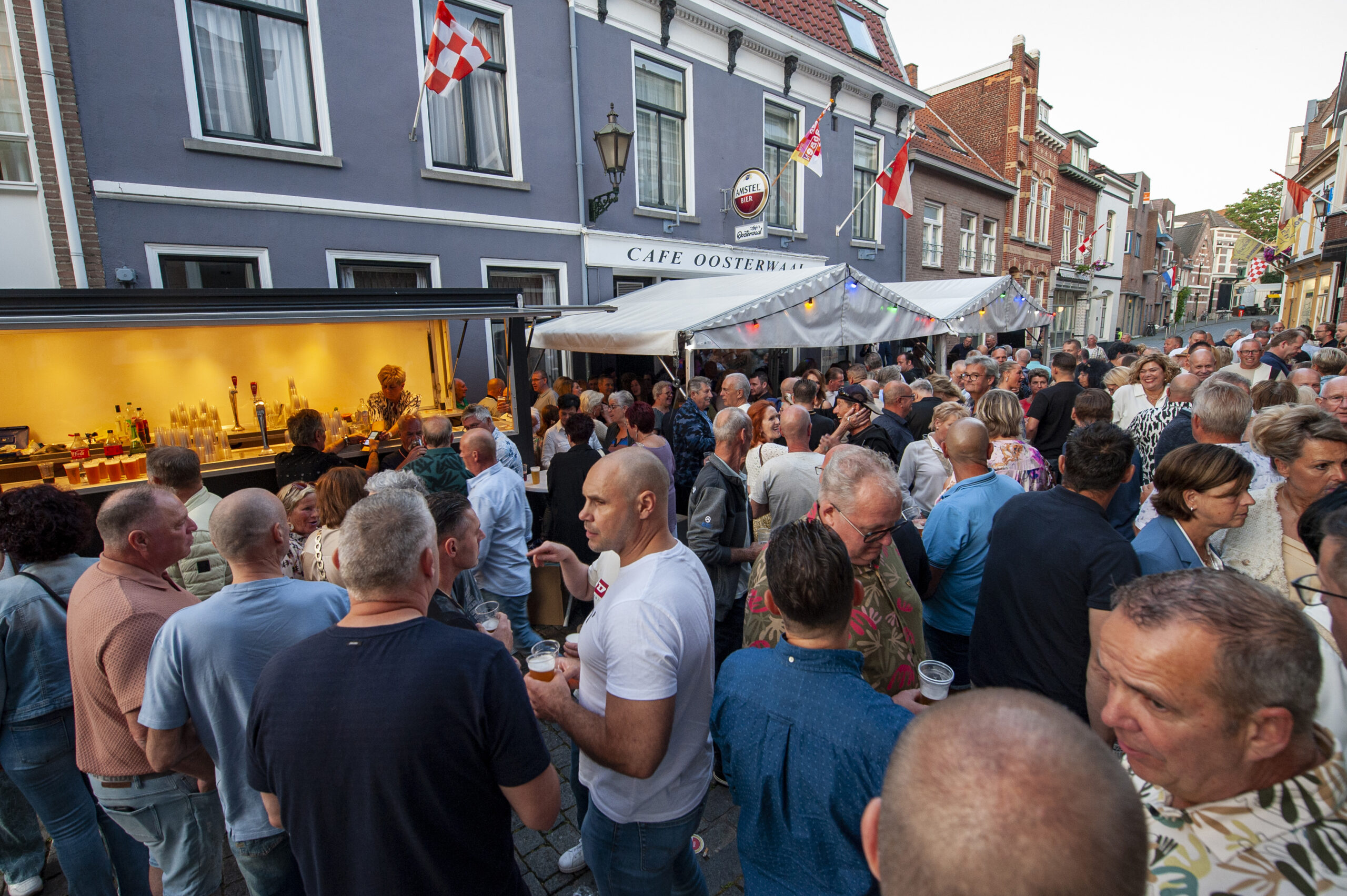 Busy street gathering with people at a cafe.