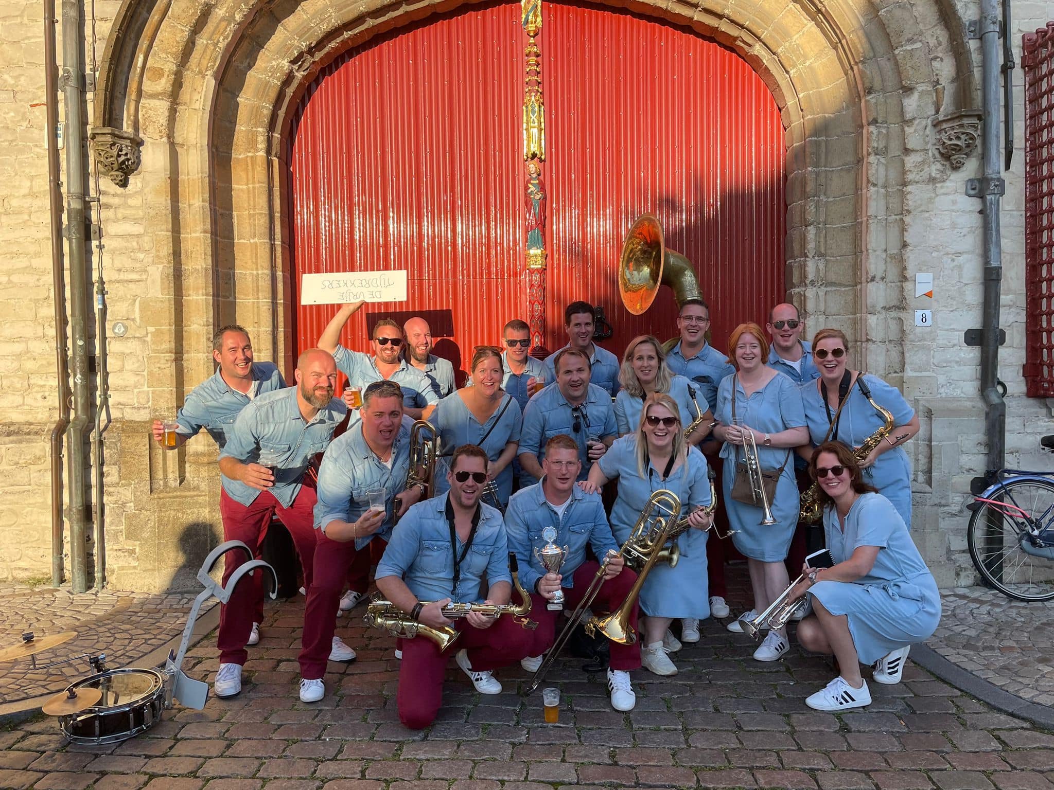 Muzikantenposeren voor historische rode deur in zonlicht
