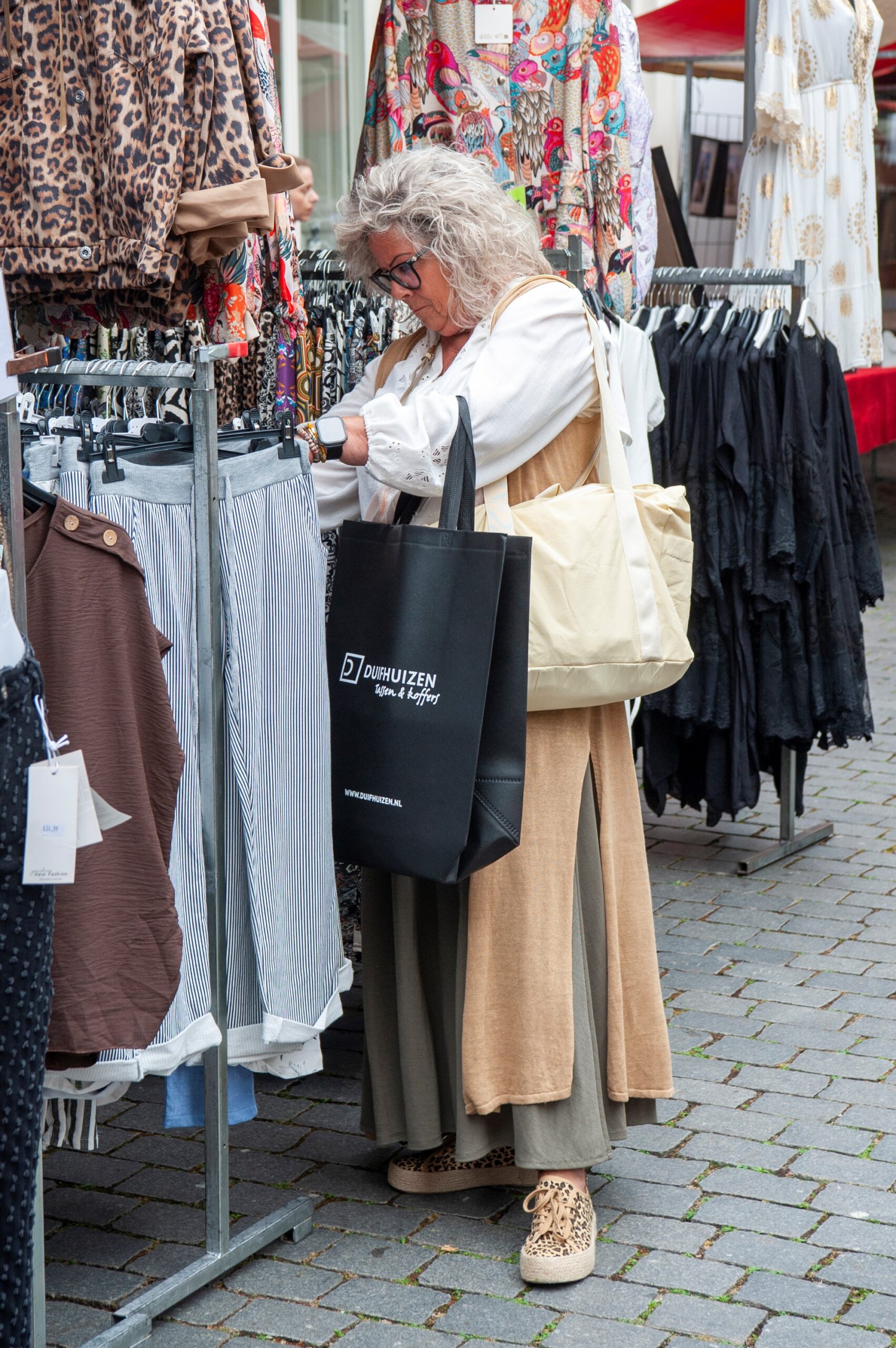 Vrouw winkelt op markt vol kleding - Bergen op Zoom