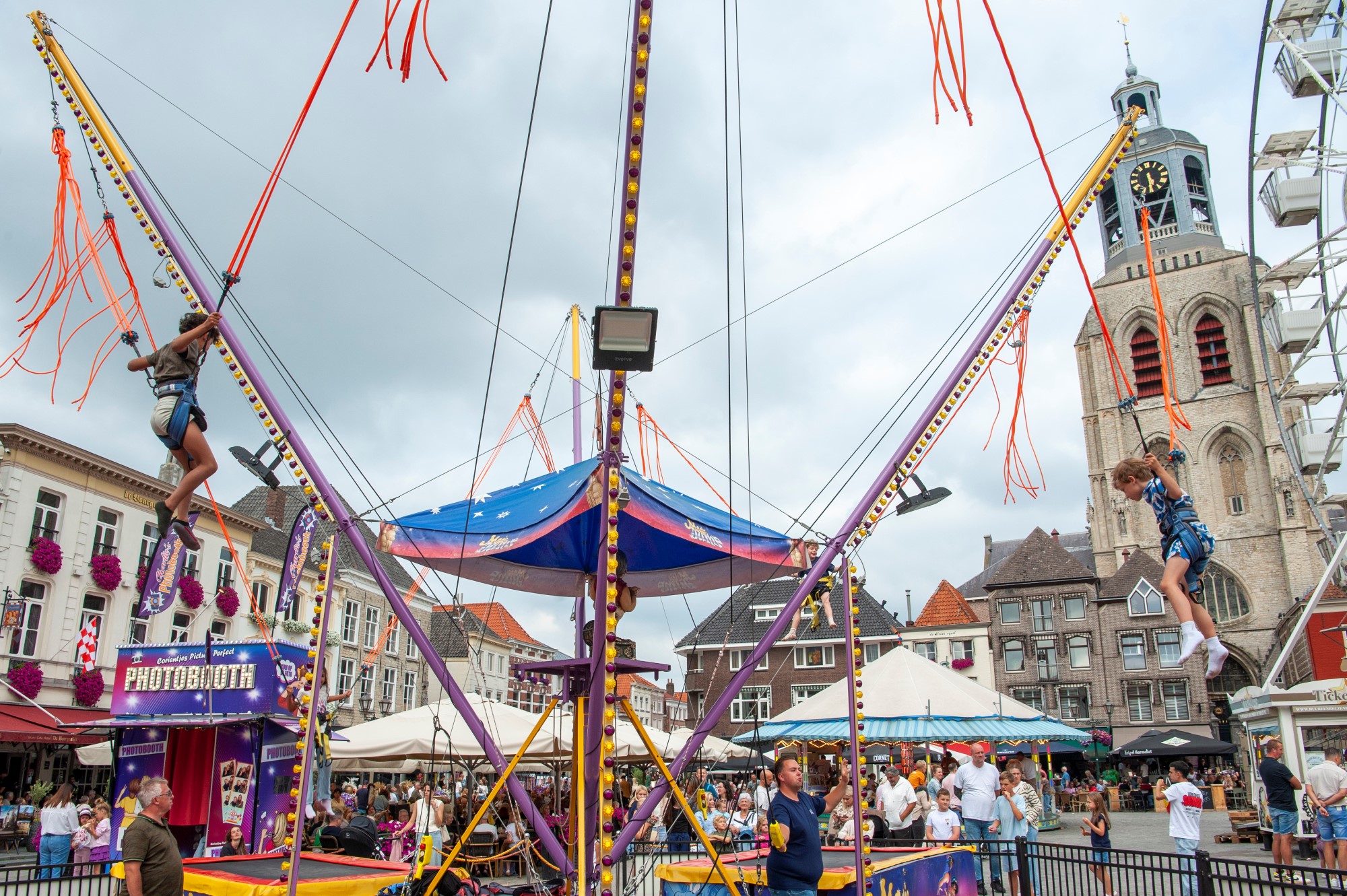 Kermisattracties en toren op bruisend stadsplein - Bergen op Zoom