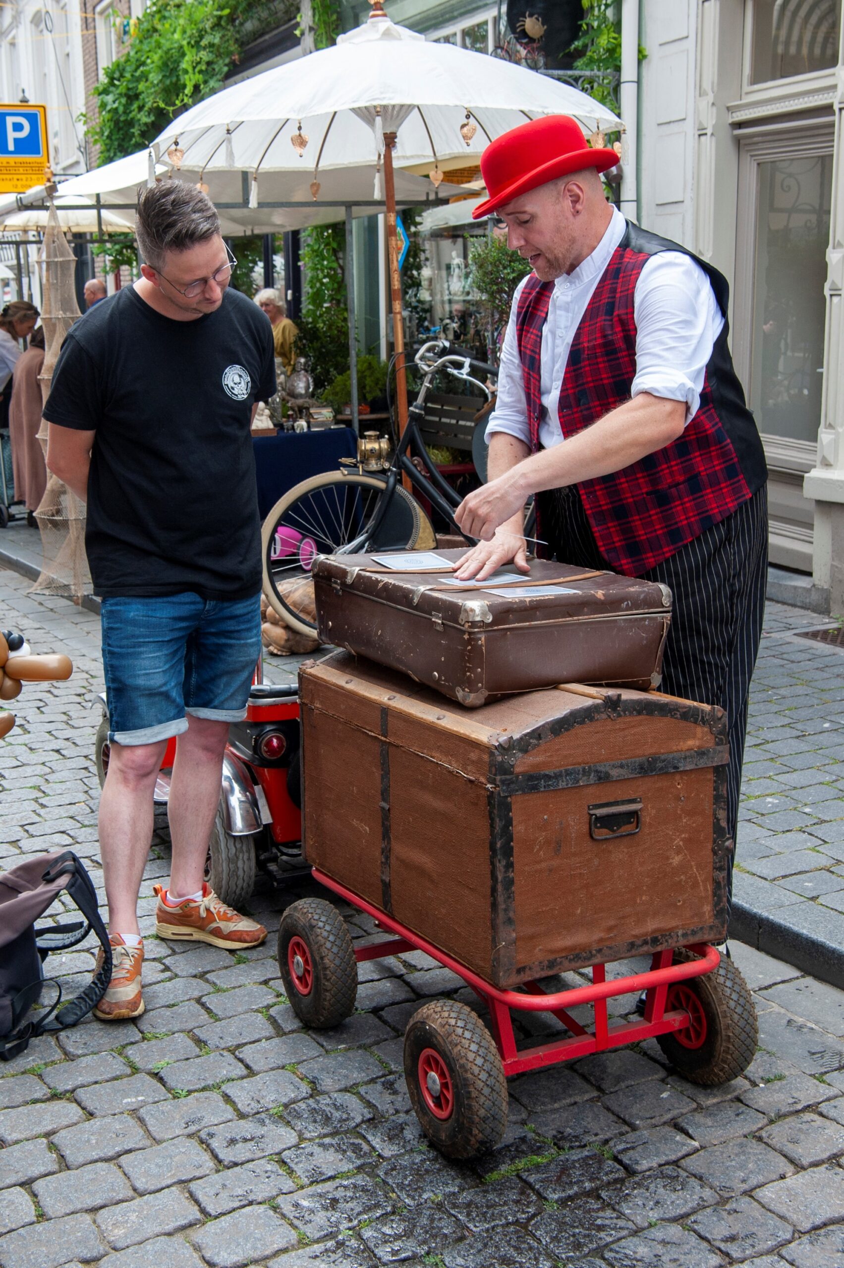Man in rood hoed met kist op straat - Bergen op Zoom